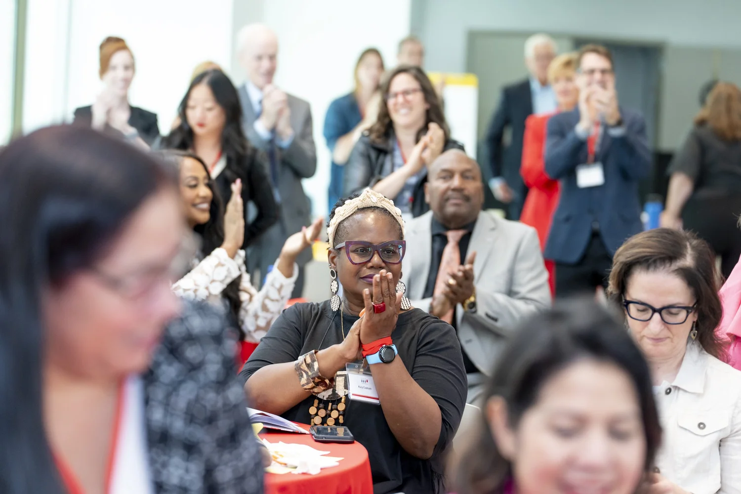 A packed ballroom of attendees applauding at a past Power Up conference